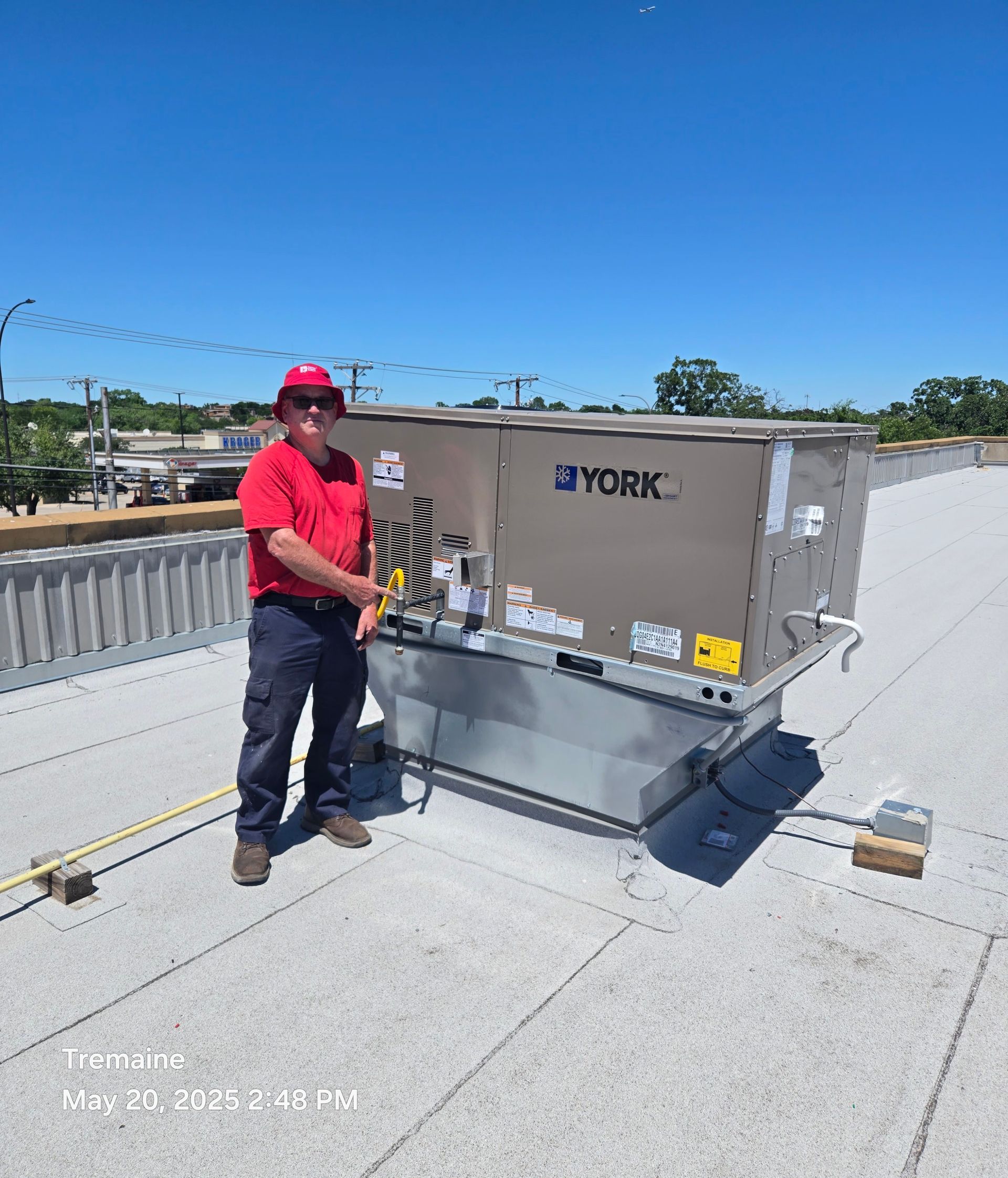 Man in hat working on large industrial equipment outdoors.