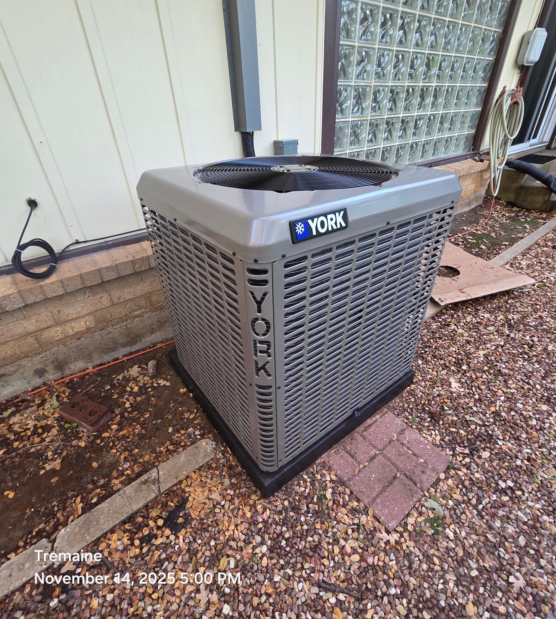A York air conditioning unit sits on a concrete pad next to a building.