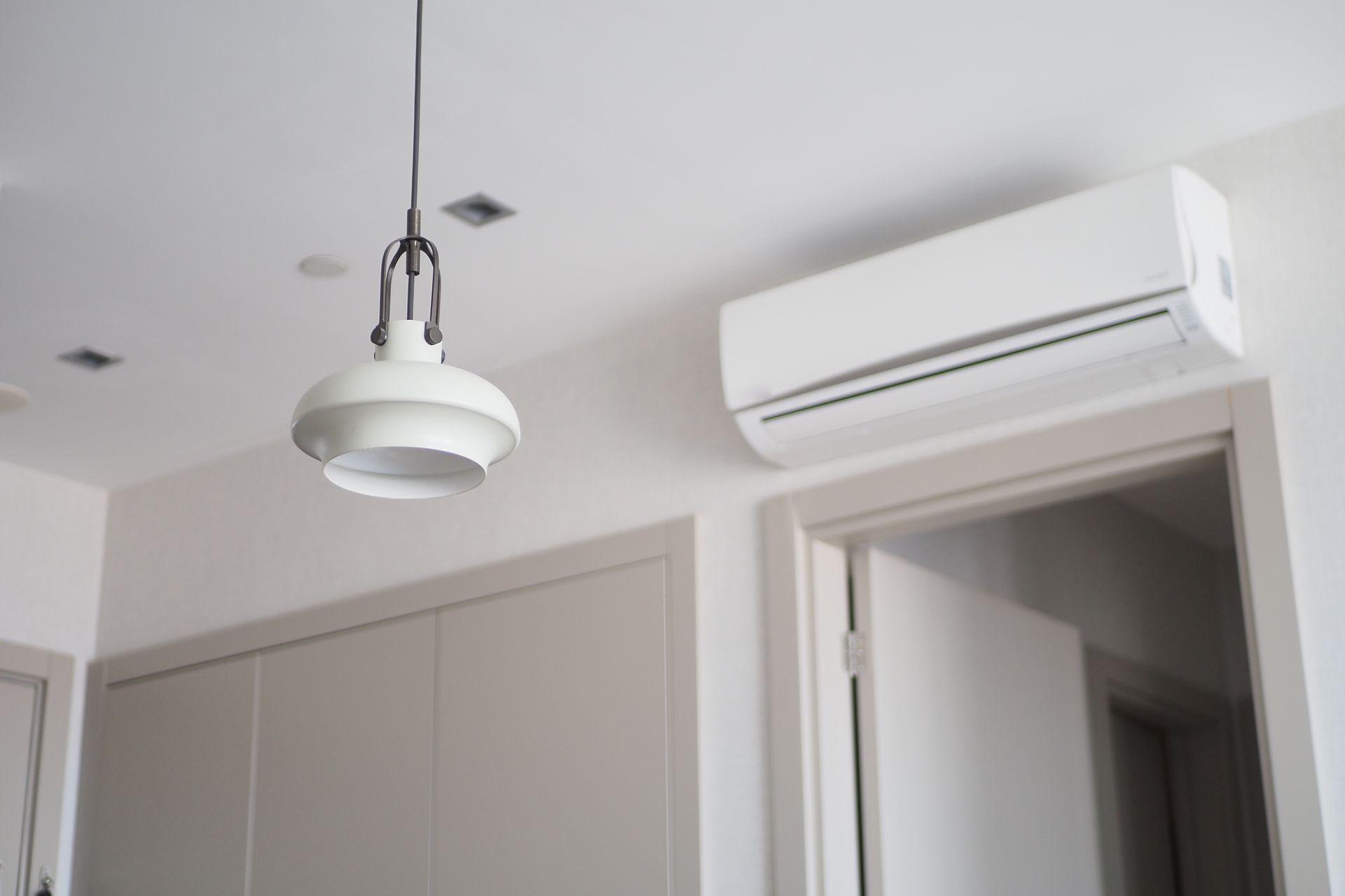 White ceiling with pendant light and air conditioner over a doorway.