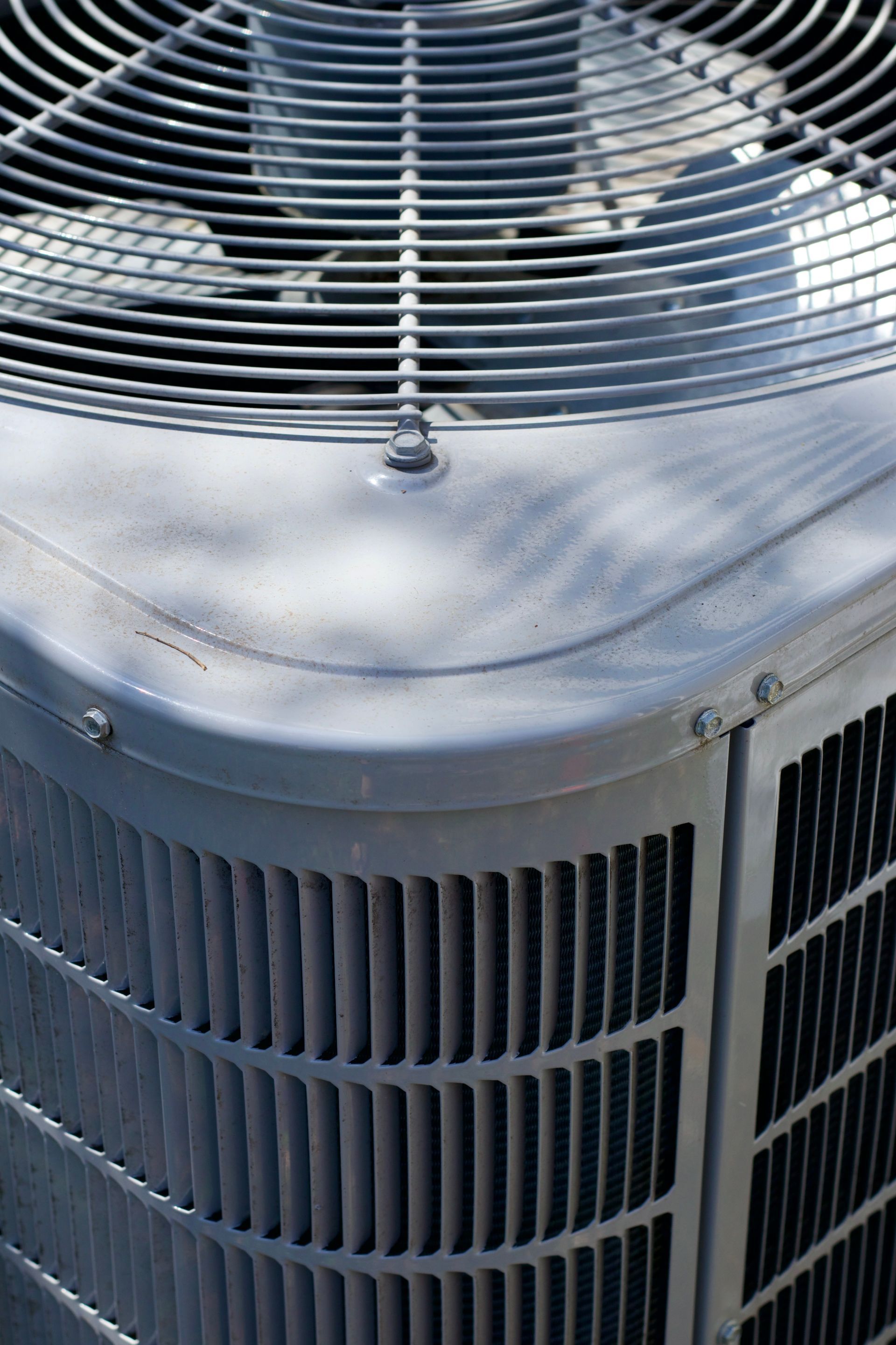 Gray air conditioning unit with a fan and vertical metal fins.