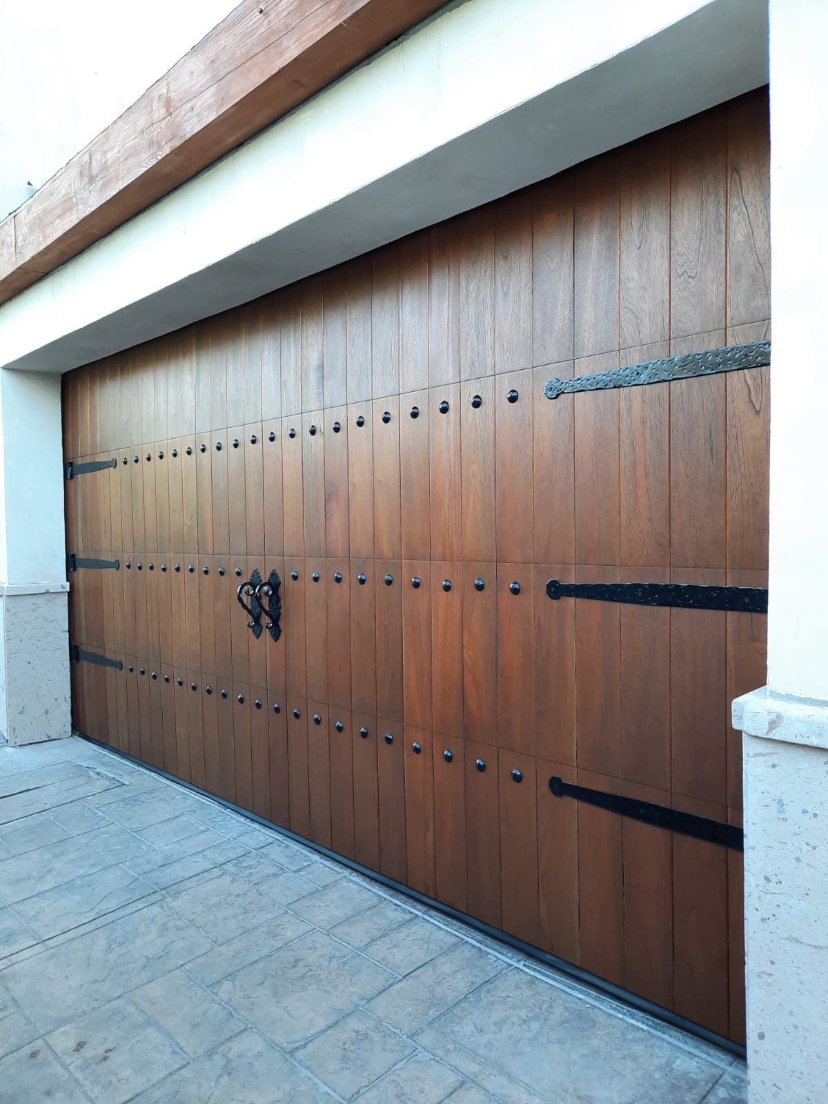 Wooden garage door with black hinges and studs.