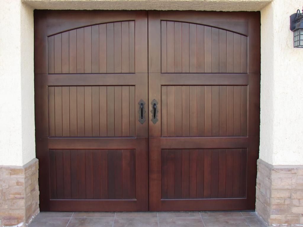 Dark wood double garage doors with arched top and vertical panels.