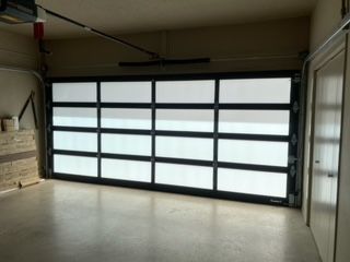 A garage interior with a closed glass-paneled garage door. Beige walls, concrete floor.