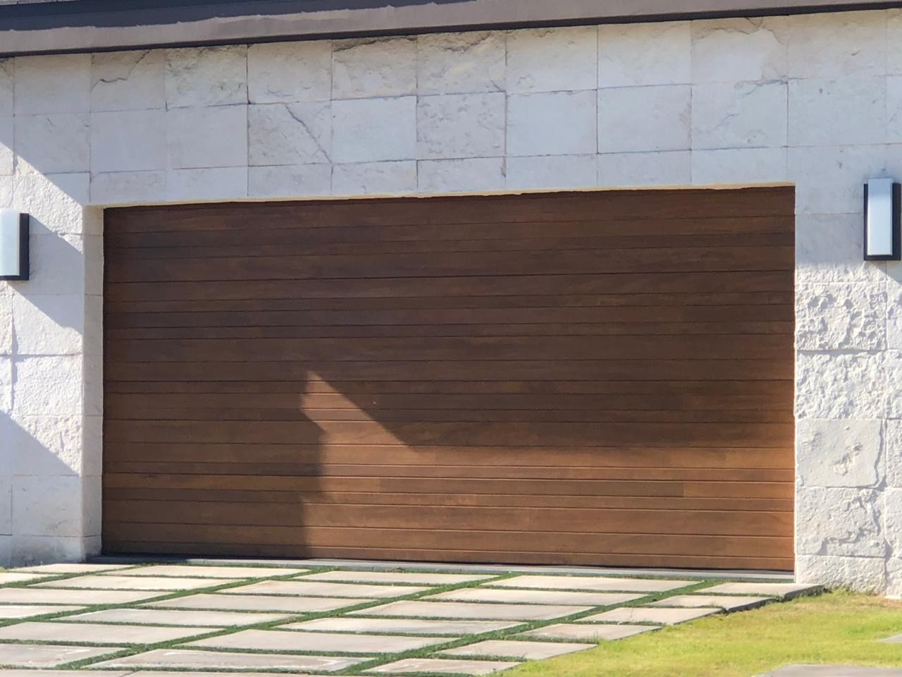 Brown horizontal slat garage door in white stone facade.