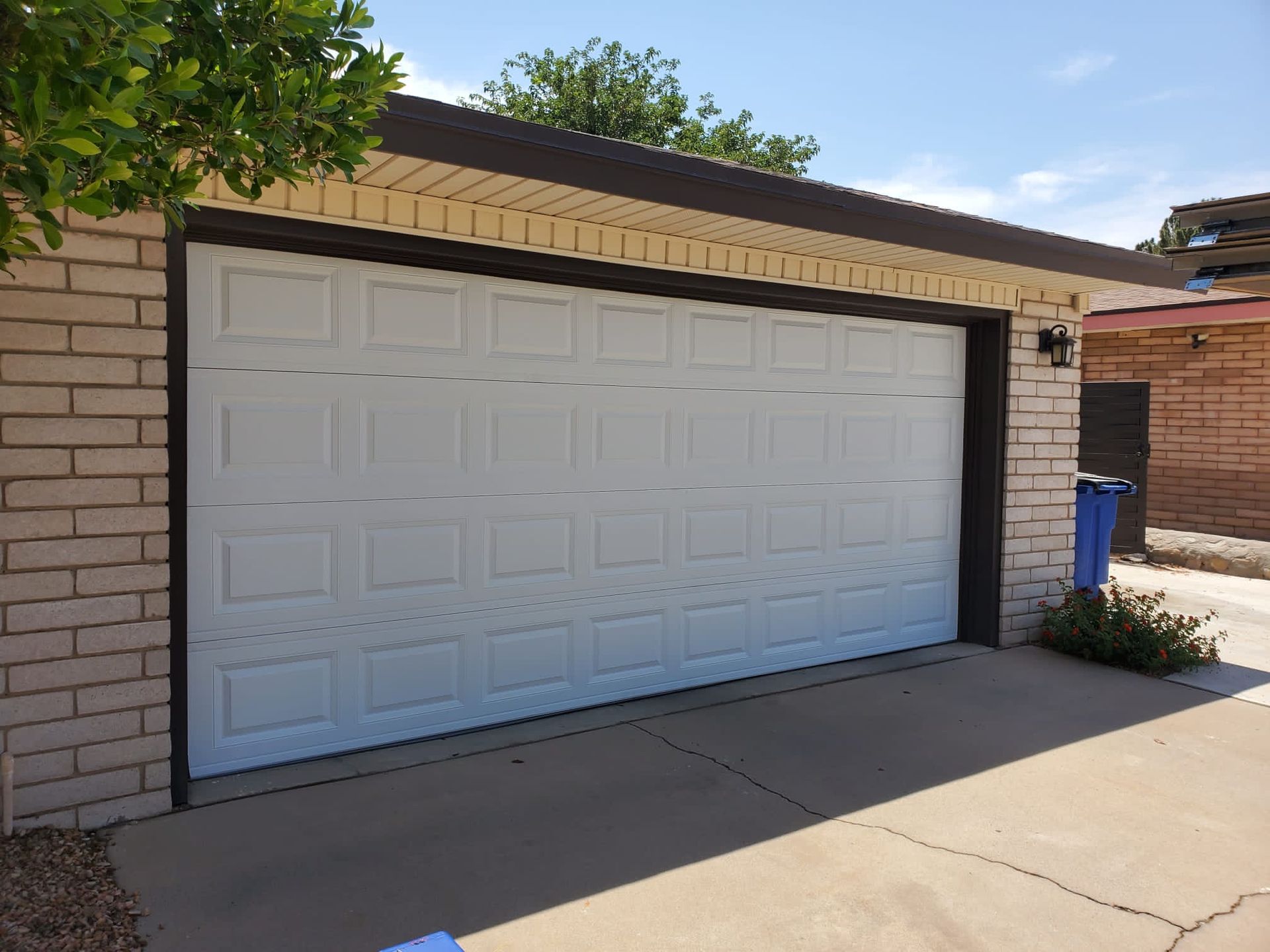 White garage door on a brick building with a concrete driveway.