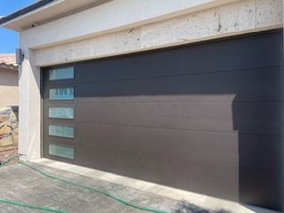 Dark gray modern garage door with four rectangular glass panels on the left.