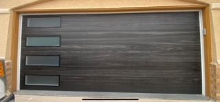 Dark brown garage door with four rectangular windows. Beige trim.