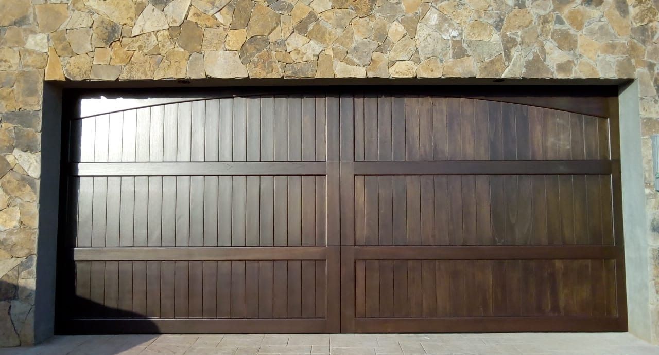 Brown wooden garage door with vertical planks, set in stone wall.