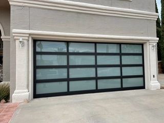 Black-framed garage door with frosted glass panels, set in a light-colored stucco building with decorative columns.