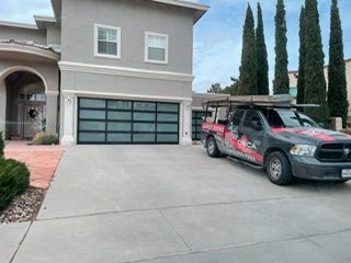 Gray house with black garage door and truck parked in the driveway.