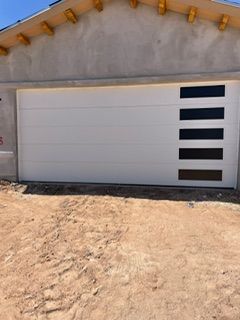 White garage door with four horizontal lines, vertical black/brown tinted windows on the right side.