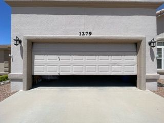 Garage door partially open; light tan stucco exterior, house number 