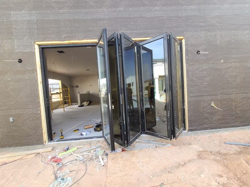 Black folding doors installed in a building opening; construction site.