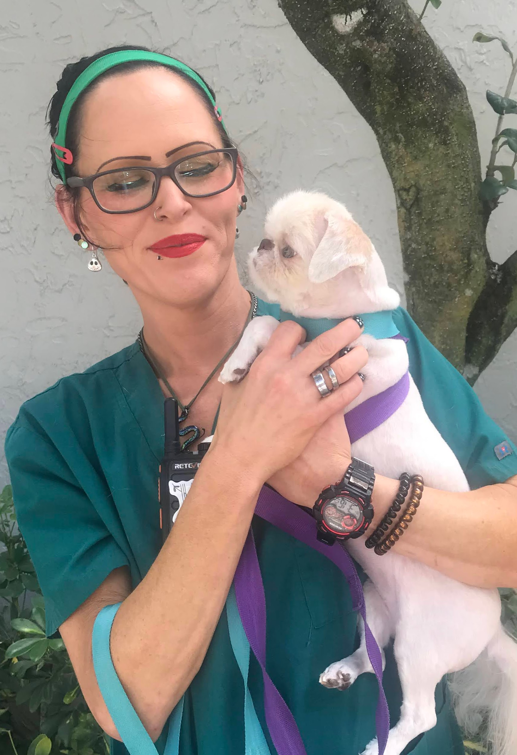 A vet is holding a small white dog in her arms.