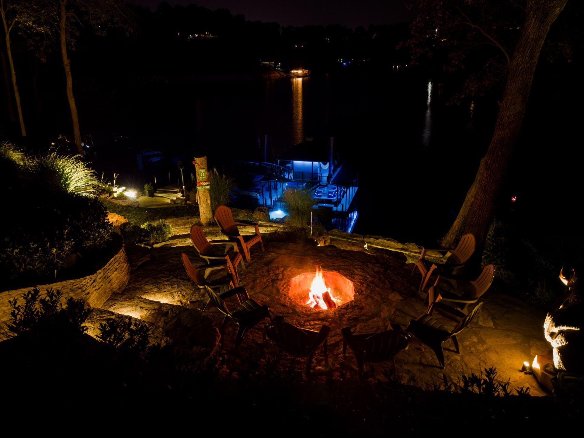 A fire pit with chairs around it is lit up at night.