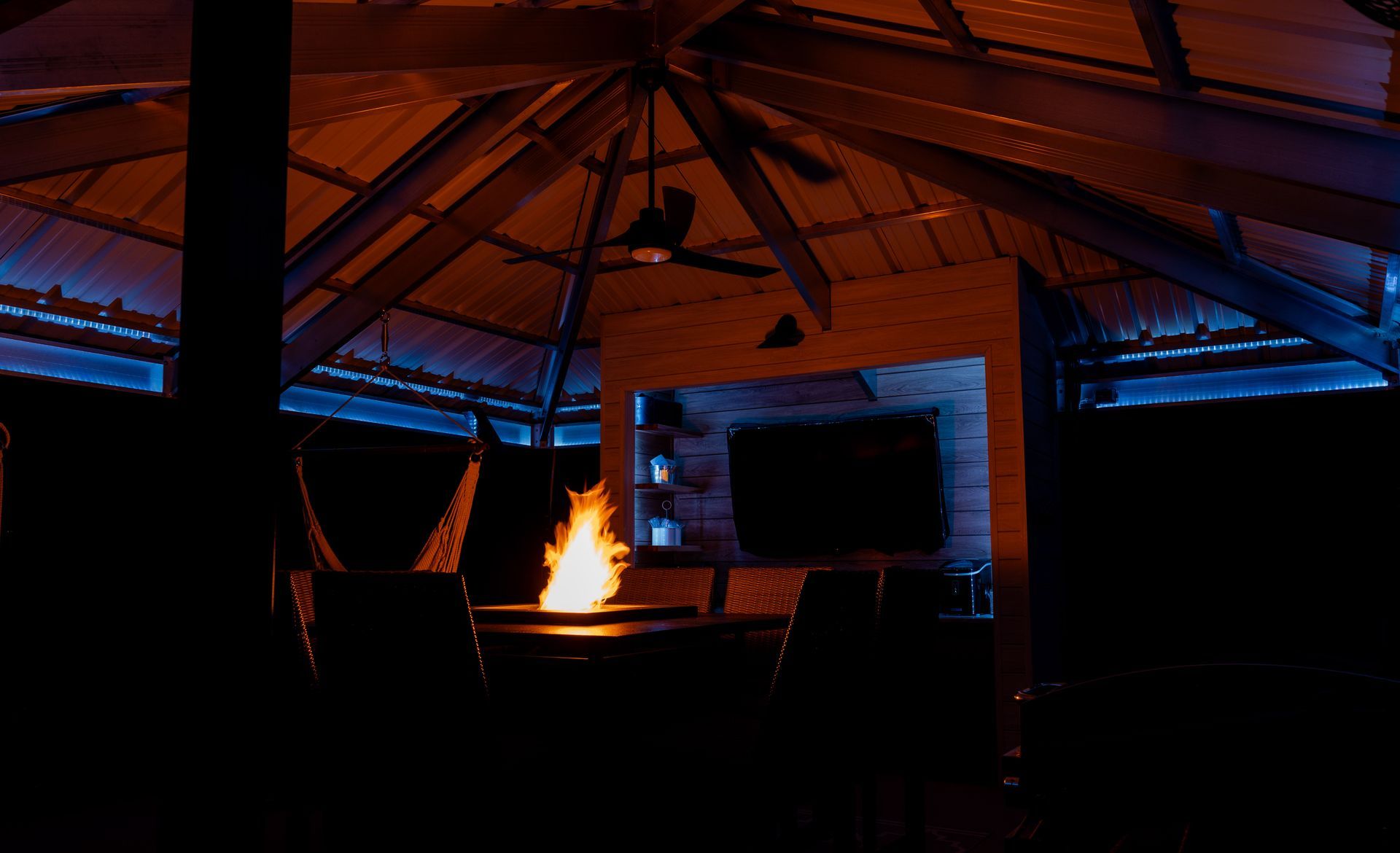 A gazebo with a fire pit and a ceiling fan