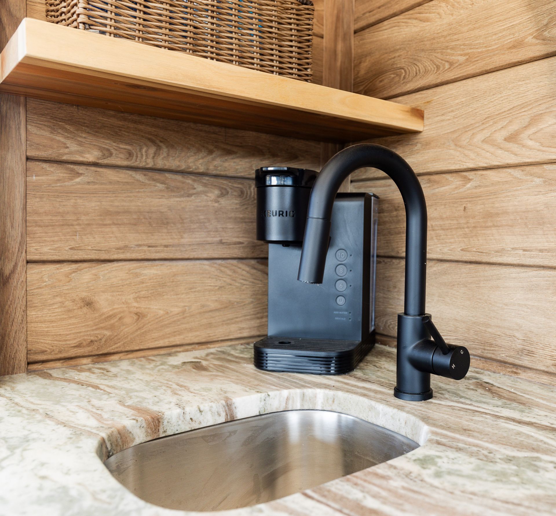 A stainless steel sink with a coffee maker on top of it