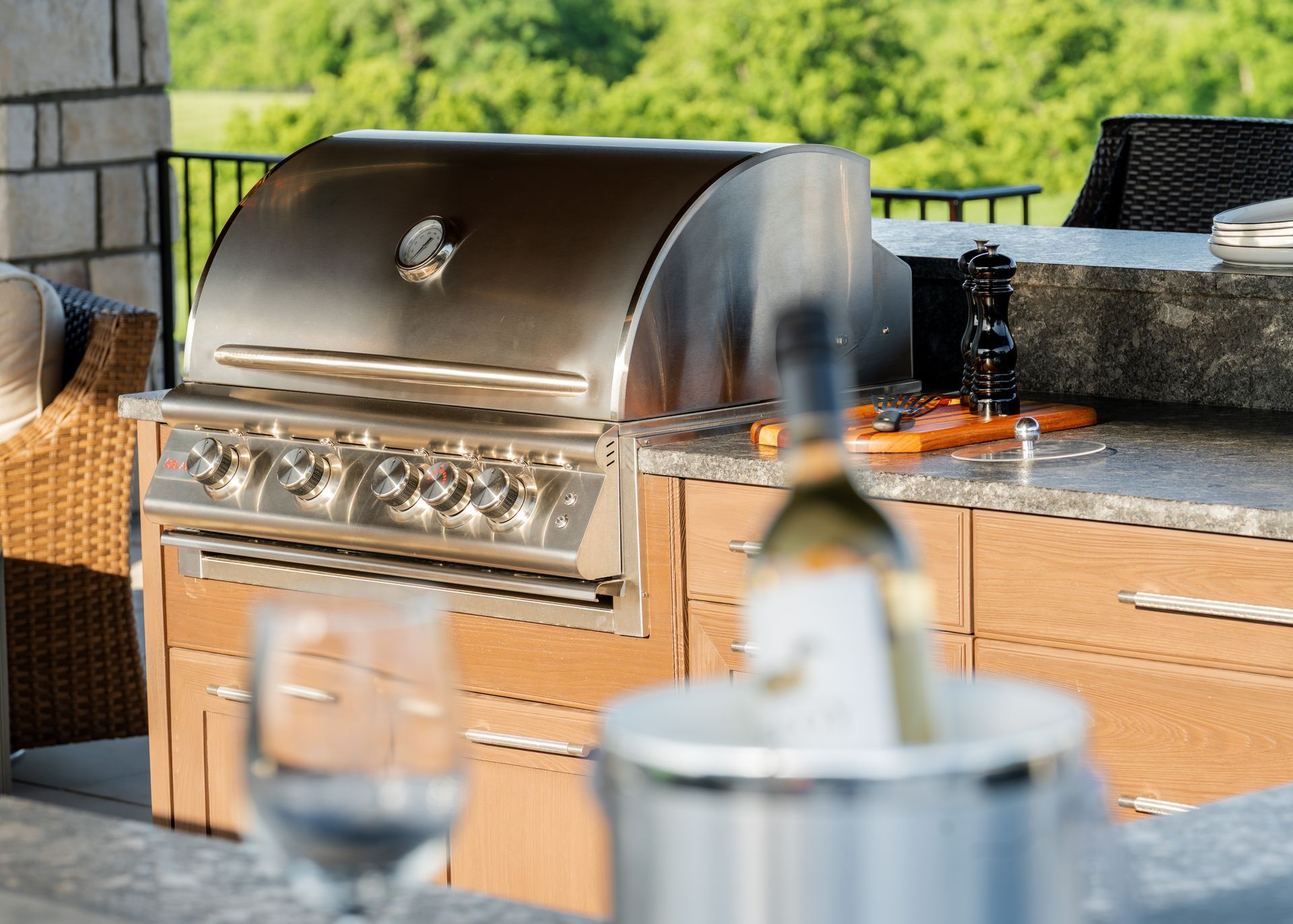 A bottle of wine and a glass of wine are on a table next to a grill.