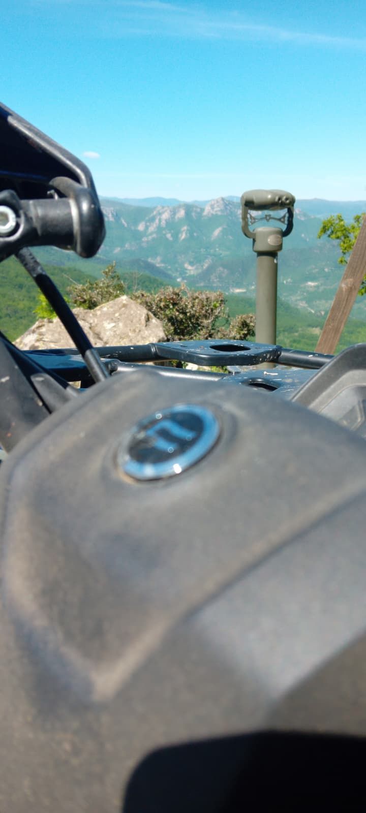 Motorcycle dashboard with road and mountains ahead under a clear blue sky