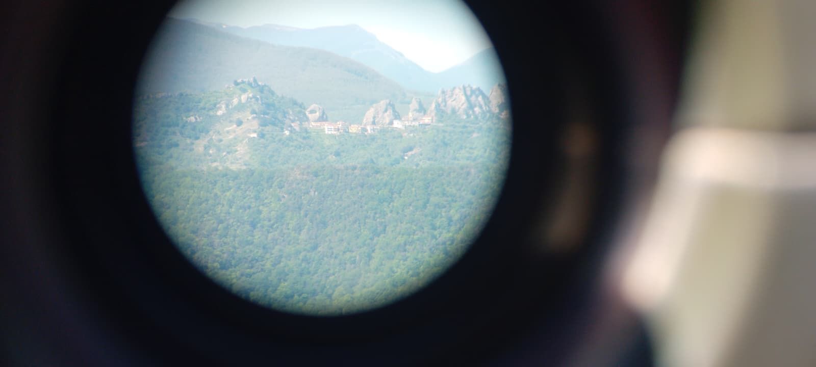 Blurred mountain landscape seen through a circular lens with dark vignette edges