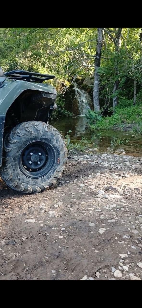 ATV tire on a muddy dirt trail in a wooded area