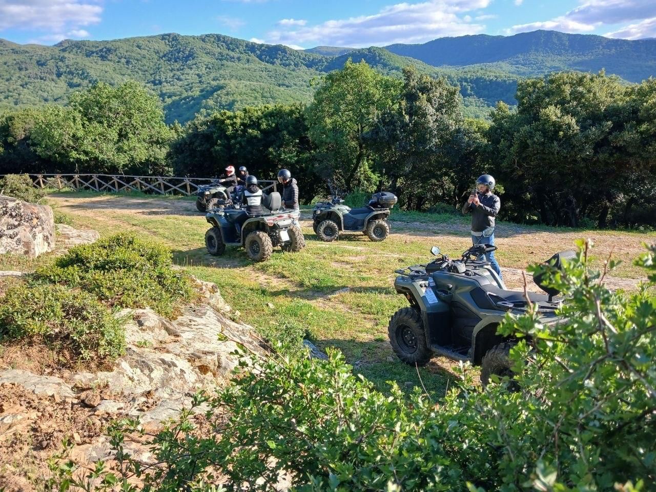 ATV riders on a dirt trail in a green mountain landscape