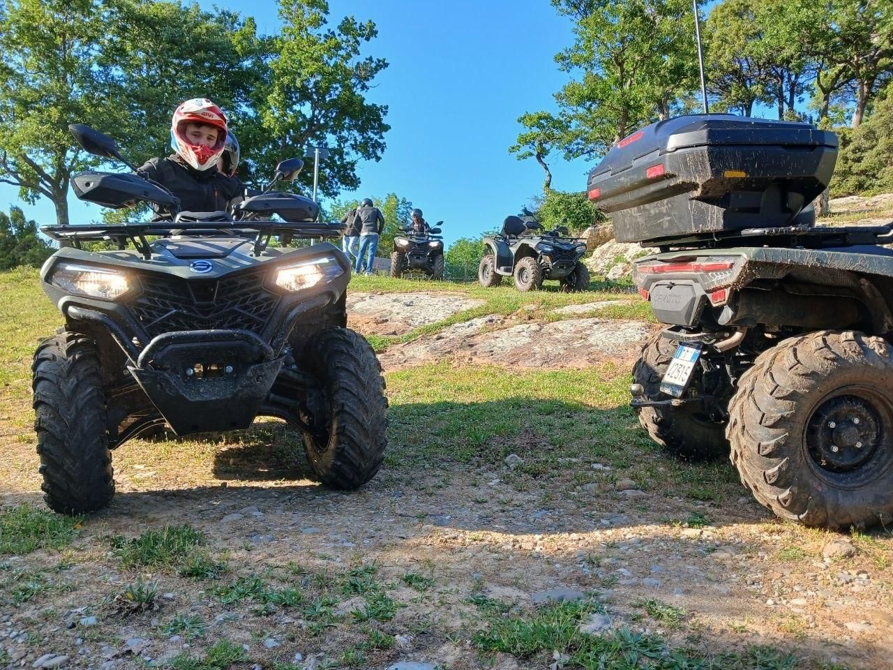 ATV riders on muddy off-road trails under a blue sky