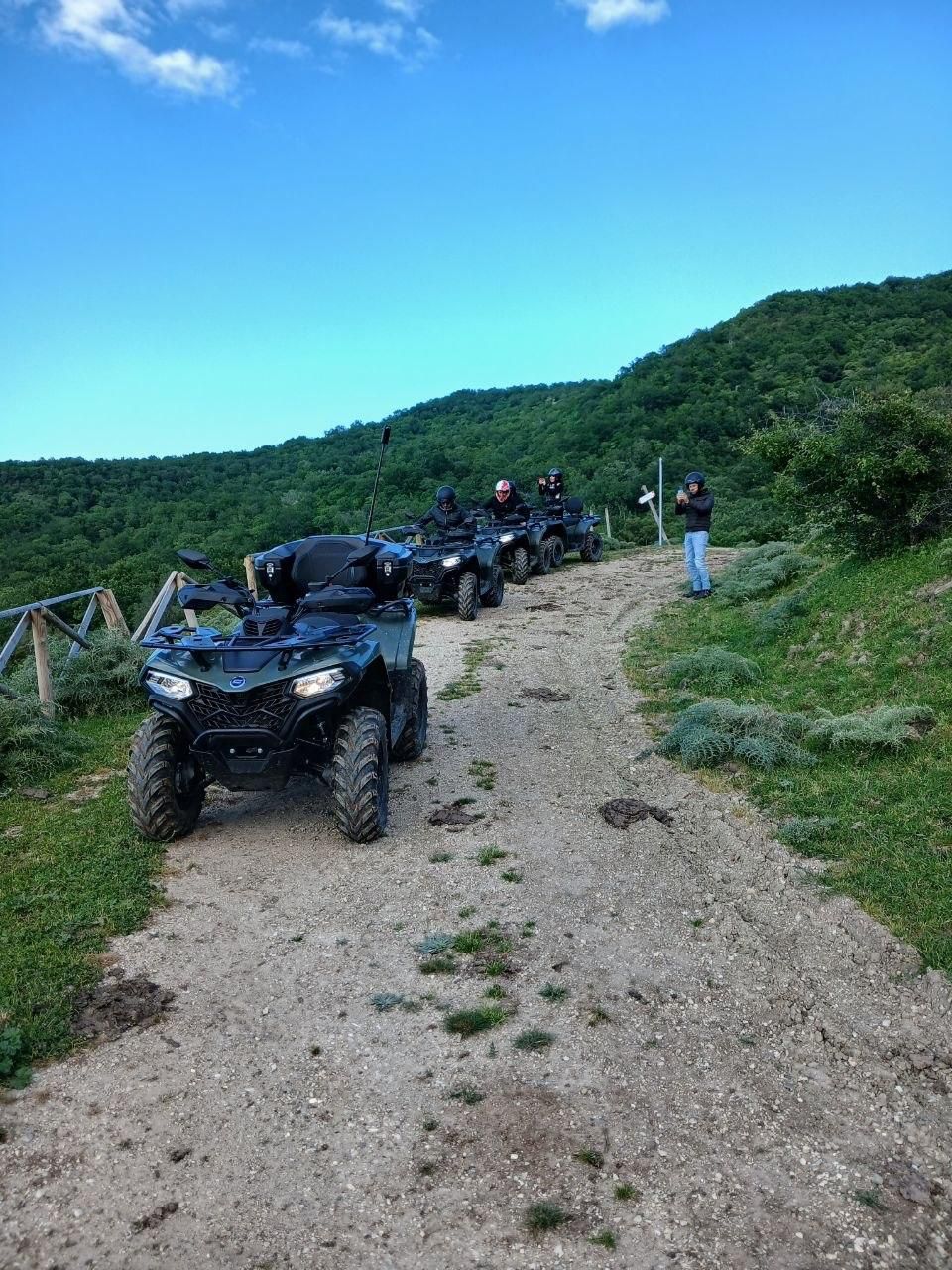 ATVs on a gravel trail in a green hillside landscape under a blue sky