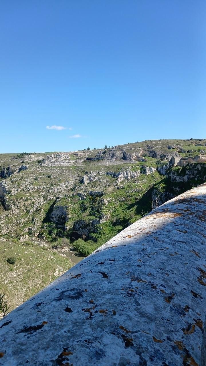 Rocky hillside under a clear blue sky, with a white stone ledge in the foreground.