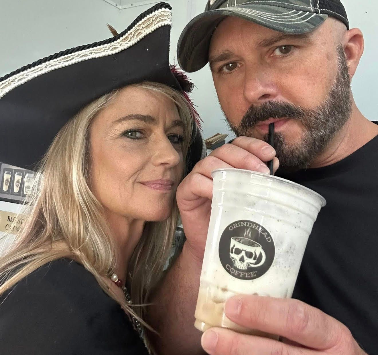 Interior of a shop with tables and chairs, displays of merchandise, and a TV screen.