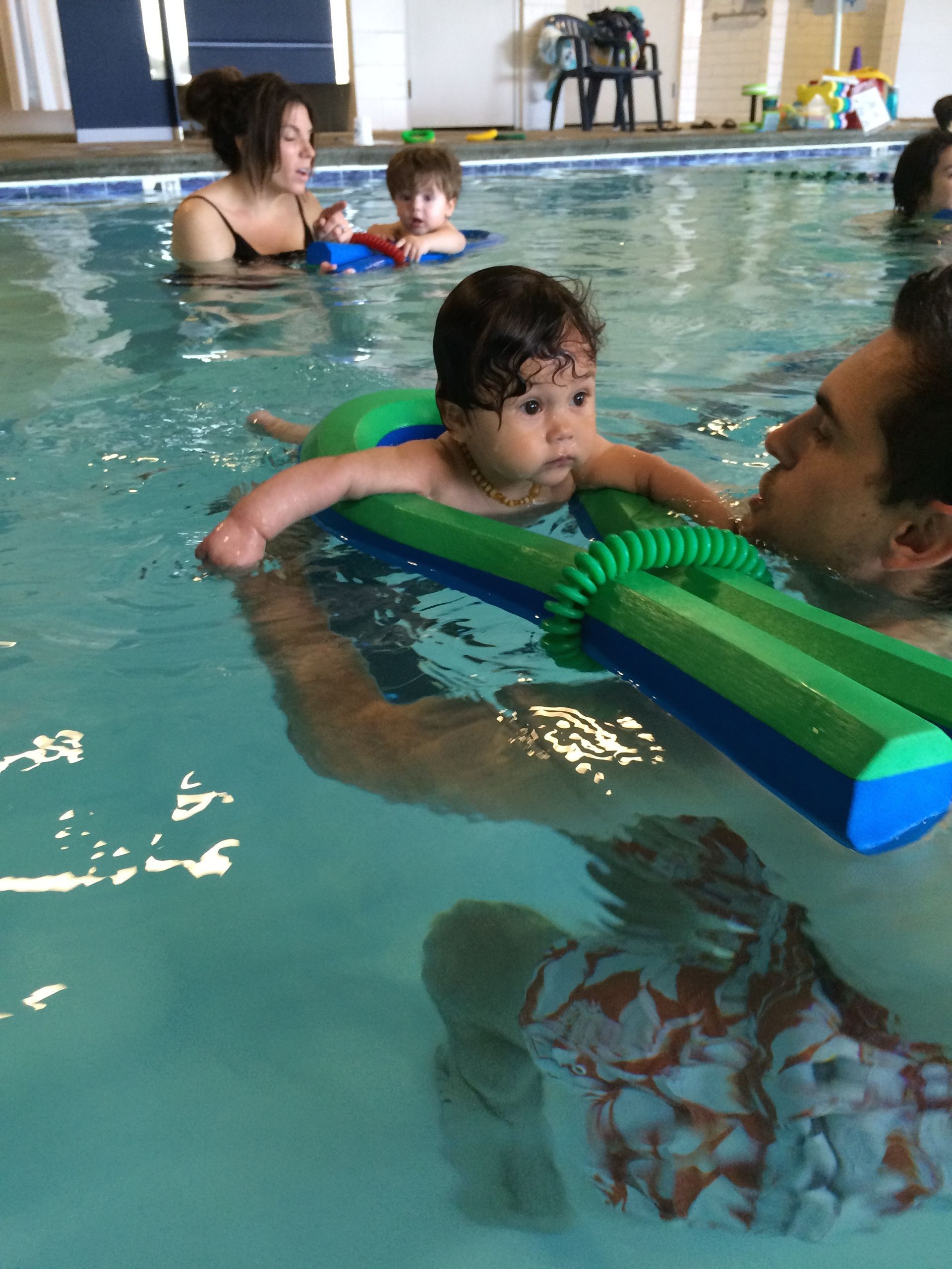 A man is holding a baby in a swimming pool