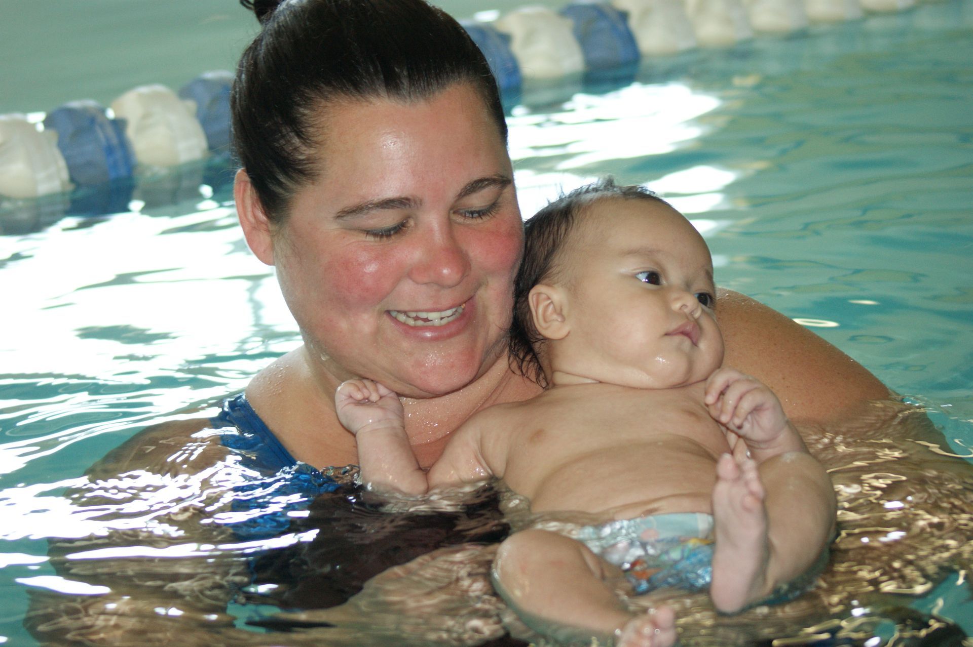 A woman is holding a baby in a swimming pool