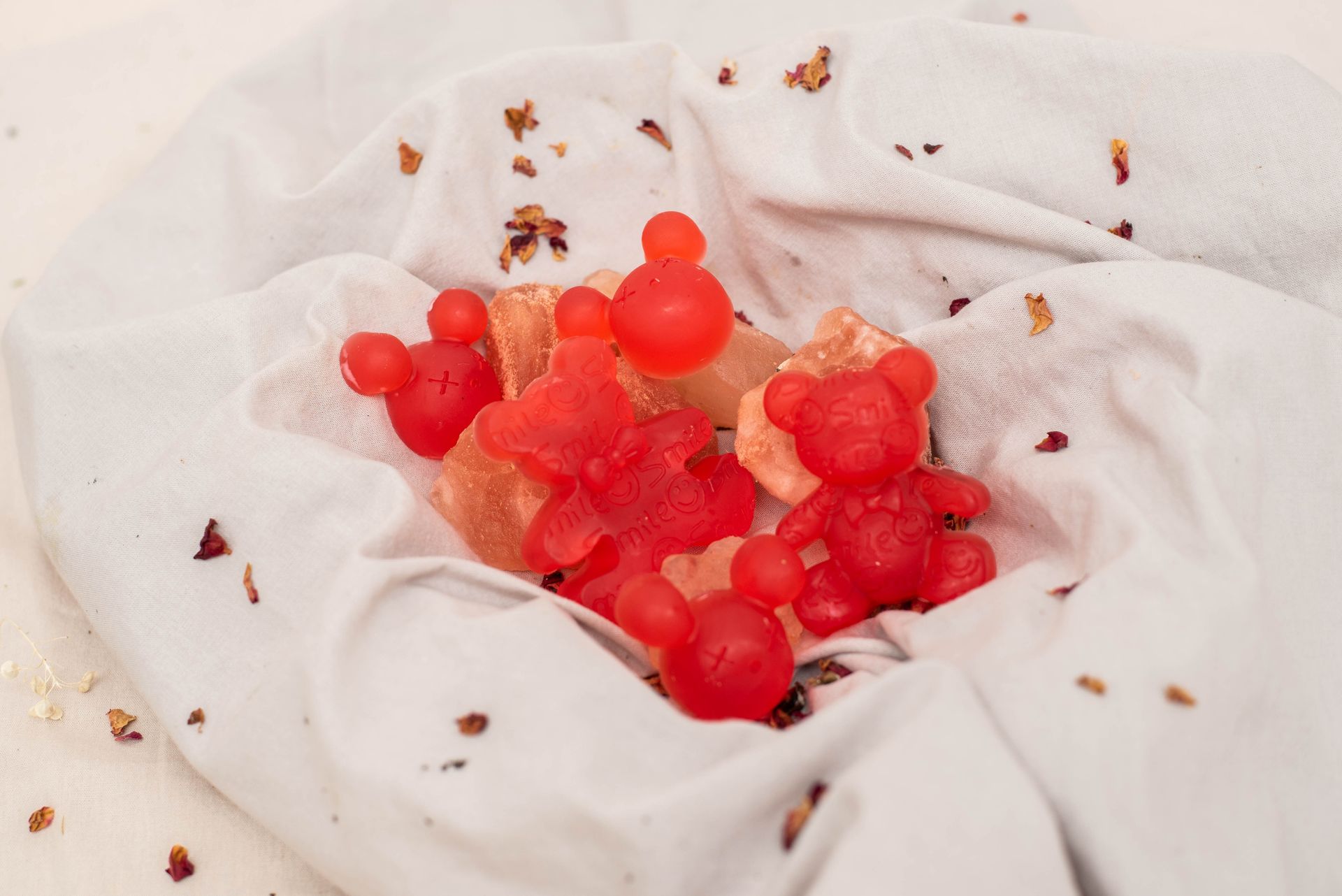 Caramelos de goma de osito rojo envueltos en un paño blanco, con trozos esparcidos por todas partes.