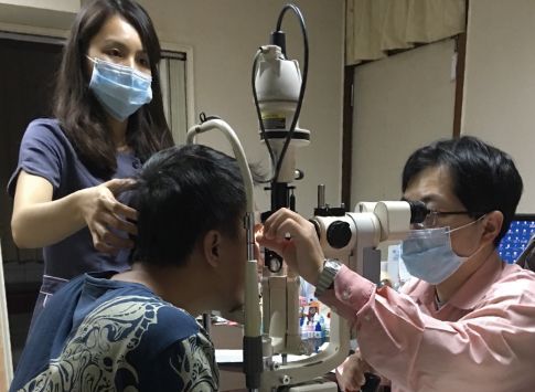 協助外勞醫療就醫與定期體檢,眼科醫師使用裂隙燈儀器檢查移工眼睛健康狀況。