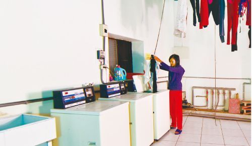 聖力國際宿舍管理人員協助維護寬廣建全的移工生活空間,操作工業洗衣設備確保環境整潔。