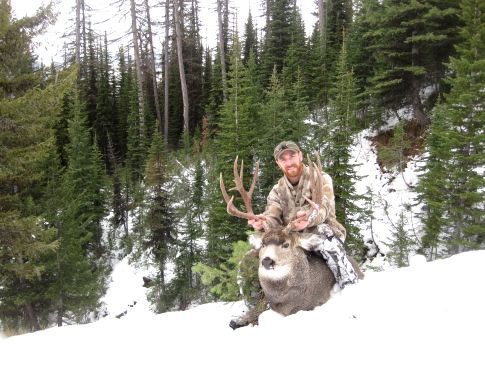 A man is sitting on the back of a deer in the snow.