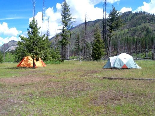Two tents in a field with mountains in the background
