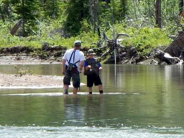 A man and a boy are fishing in a river.