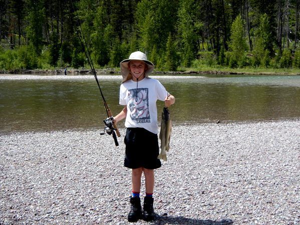 A young boy is holding a fishing rod and a fish.