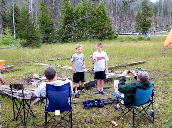 A group of people are sitting around a campfire in a field.