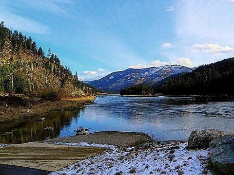 A river with mountains in the background and snow on the ground