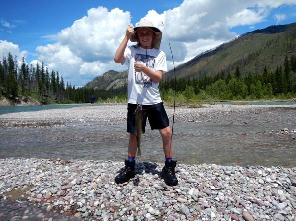 A young boy is holding a fishing rod in front of a river.