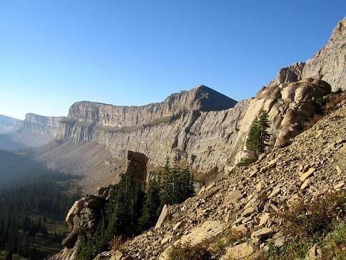 A mountain covered in rocks and trees with a blue sky in the background