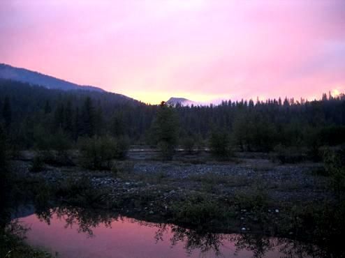 A sunset over a river with mountains in the background