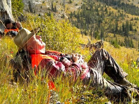 A man is laying in the grass on top of a hill.