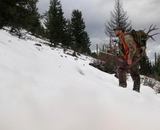 A man with antlers is standing in the snow
