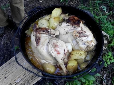 A chicken and potatoes are cooking in a dutch oven.