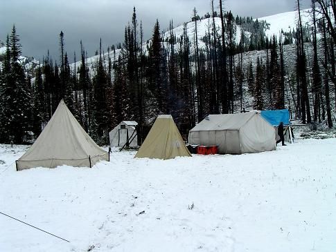 A group of tents in the snow with mountains in the background