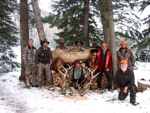 A group of men are posing for a picture with a deer in the snow.