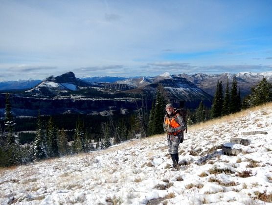 A man with a backpack is walking up a snowy hill.